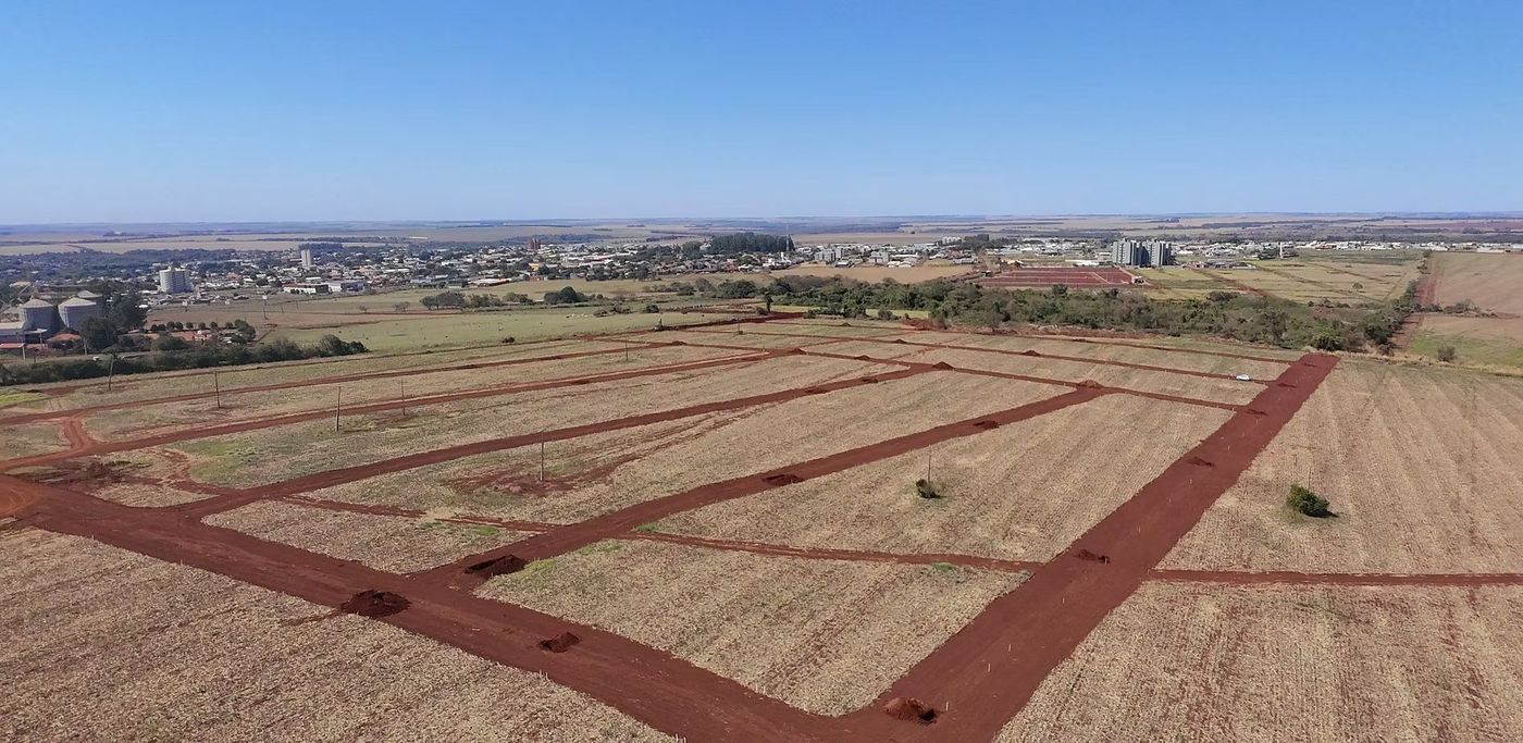 Vista aérea do terreno do Altos do Horto com as ruas já demarcadas em terra vermelha e a cidade ao fundo